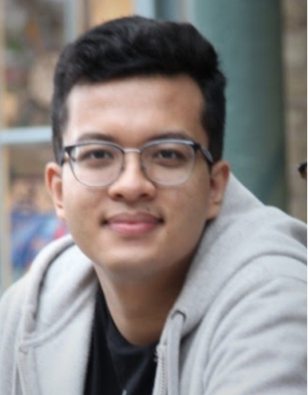 Colour image of Nirajan wearing glasses and a grey hoodie looking directly at the camera. This man with a cloud computing career has black hair and seems to have had a fresh haircut.